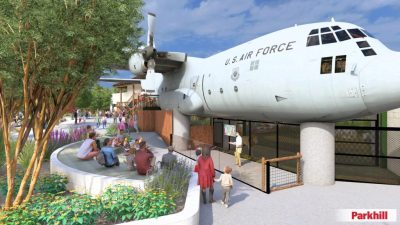 Architectural rendering of a US Air Force C-130 aircraft mounted above a zoo lion habitat, with visitors seated at an amphitheater below.