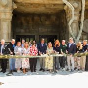 A long line of people cut a ribbon in front of the stone elephant-head facade of Tulsa Zoo's renovated elephant building.