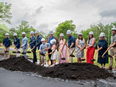 A line of people in hard hats hold gold shovels over a mound of soil at the Memphis Zoo groundbreaking for Stingrays at Mangrove Cove.
