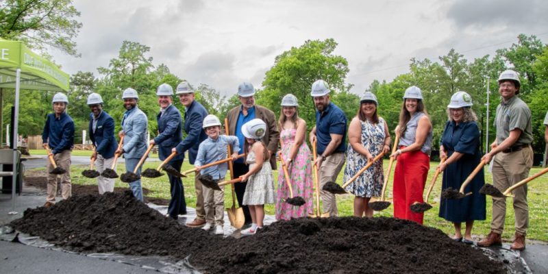 A line of people in hard hats hold gold shovels over a mound of soil at the Memphis Zoo groundbreaking for Stingrays at Mangrove Cove.