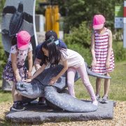 Four children climb on a life-size sea turtle sculpture along an outdoor trail at the Virginia Aquarium.