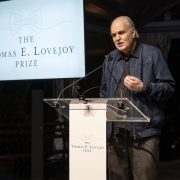 Dr. Carlos Afonso Nobre speaks at a clear lectern beside a screen reading The Thomas E. Lovejoy Prize above a line drawing of a bow tie.