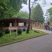 A timber lodge and paddock behind a sign reading Reindeer Ravine, with visitors walking along a path.