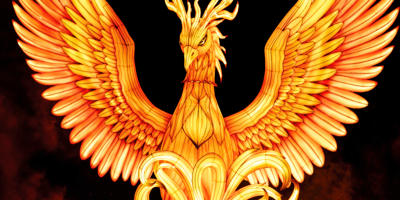A large illuminated lantern of a phoenix with outstretched wings, glowing orange and yellow against a dark sky.