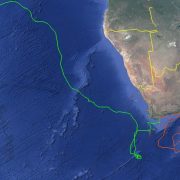 A satellite map of southern Africa and the surrounding oceans with two plotted tracks: a green line running from the southern Cape far up the Atlantic toward West Africa, and an orange line looping east from the Cape across the southwestern Indian Ocean.