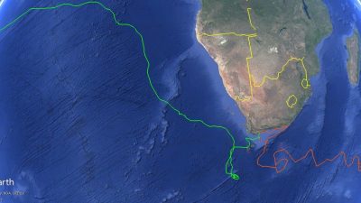 A satellite map of southern Africa and the surrounding oceans with two plotted tracks: a green line running from the southern Cape far up the Atlantic toward West Africa, and an orange line looping east from the Cape across the southwestern Indian Ocean.