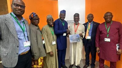 Seven delegates stand together at the CBD COP17 venue in Yerevan, two of them holding a certificate printed with the word Nigeria.
