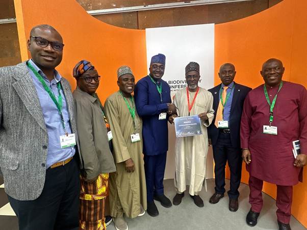 Seven delegates stand together at the CBD COP17 venue in Yerevan, two of them holding a certificate printed with the word Nigeria.
