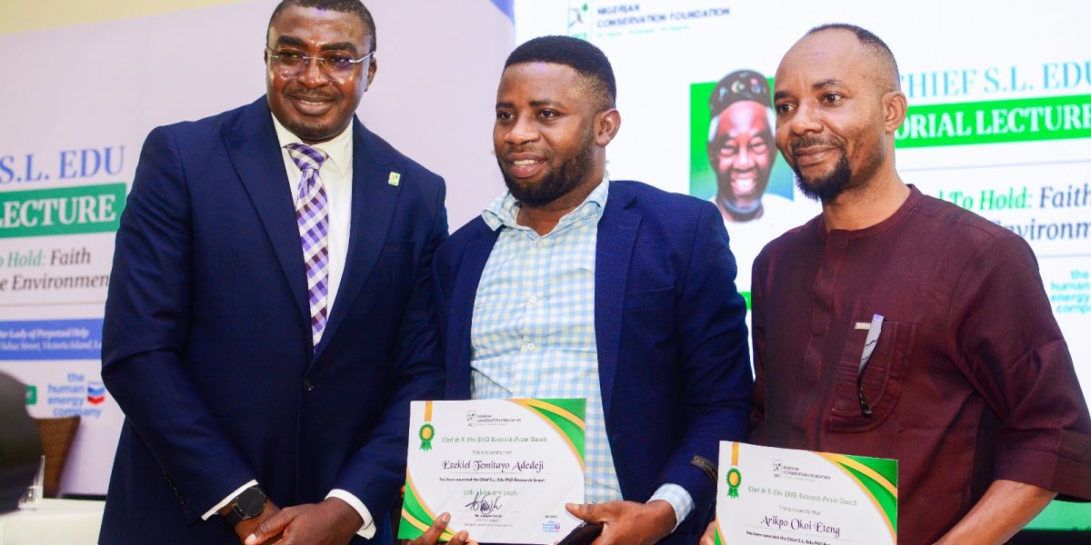 Three men stand for a photograph at the Chief S.L. Edu Memorial Lecture, two of them holding Nigerian Conservation Foundation research grant certificates, in front of a backdrop carrying the foundation's logo and the lecture title.
