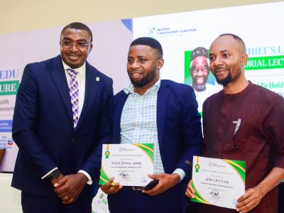 Three men stand for a photograph at the Chief S.L. Edu Memorial Lecture, two of them holding Nigerian Conservation Foundation research grant certificates, in front of a backdrop carrying the foundation's logo and the lecture title.