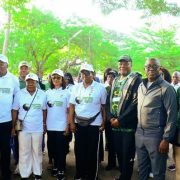 A line of walkers in white shirts reading Inspired for Climate Action stands together under trees before setting off.