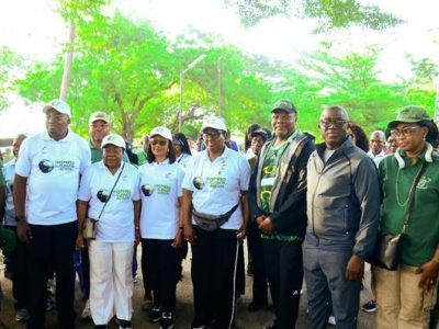 A line of walkers in white shirts reading Inspired for Climate Action stands together under trees before setting off.