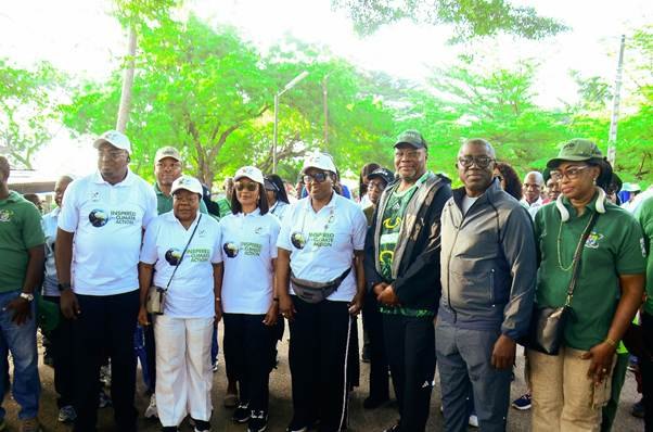 A line of walkers in white shirts reading Inspired for Climate Action stands together under trees before setting off.