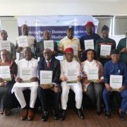 Thirteen delegates pose in two rows at the Abuja launch of Nigeria's National Business Action Plan for Biodiversity, each holding a printed copy of the plan, in front of a banner reading strengthening business engagement in Nigeria's biodiversity agenda.