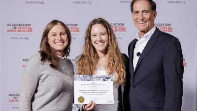 Cassandra Costello, Rochelle Stiles and Dan Ashe stand in front of an Association of Zoos and Aquariums backdrop, with Stiles holding the 2026 North American Conservation Award certificate for San Francisco Zoo and Gardens.