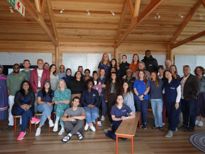 Around forty delegates to the National Sea Turtle Workshop stand and sit together for a group photograph in a timber-framed room at the Two Oceans Aquarium in Cape Town.